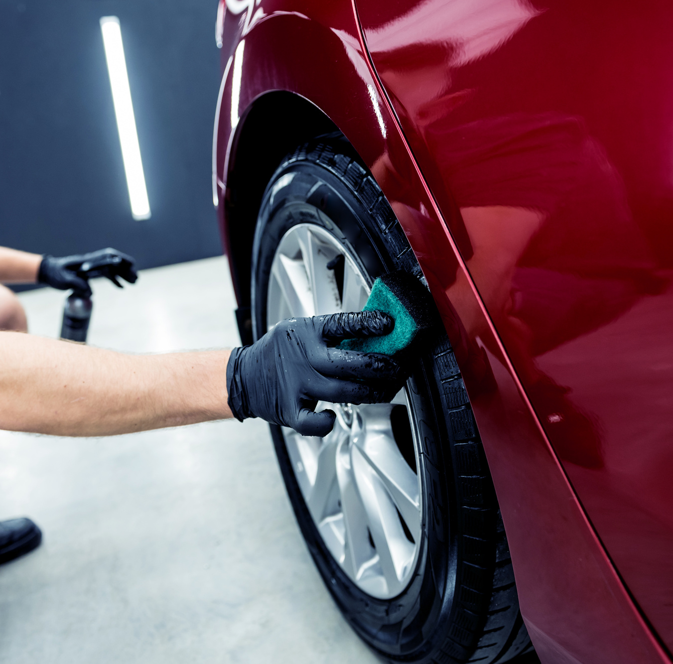 Car service worker polishing car wheels with microfiber cloth.